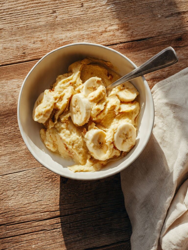 Mashed ripe banana in a white bowl showing smooth paste consistency for banana oatmeal cookies