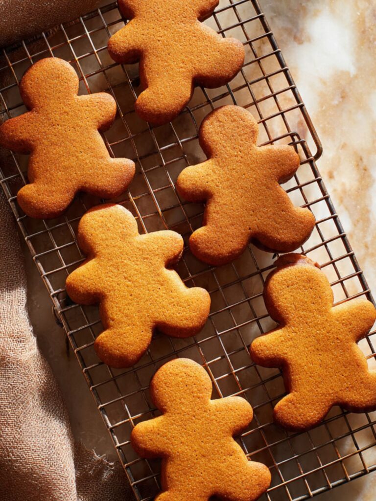 Freshly baked gingerbread men cookies cooling on a wire rack showing deep golden brown color and set edges