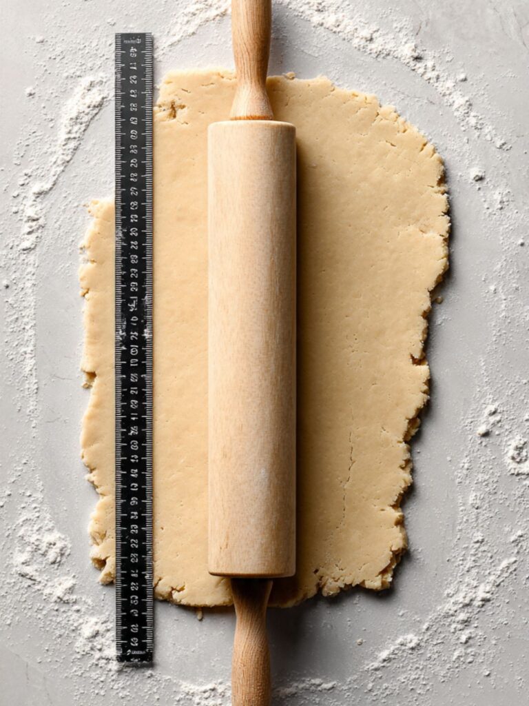 Shortbread cookie dough rolled to half inch thickness on floured surface with rolling pin