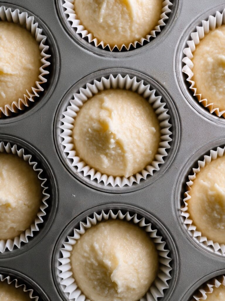 vanilla cupcake batter portioned into paper-lined muffin tin for strawberry crunch cupcakes recipe